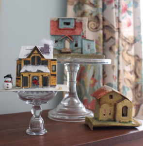 Antique Christmas village houses on cake pedestals.